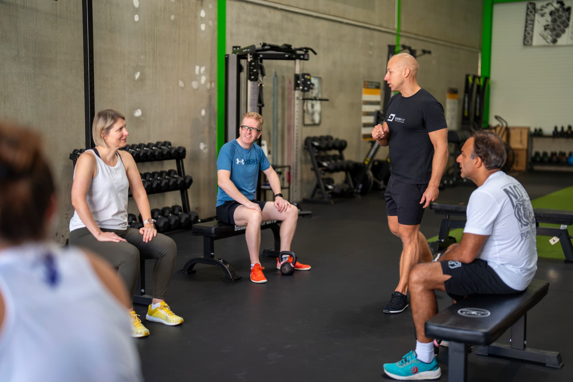 Atti coaching a member through a squat session at the gym